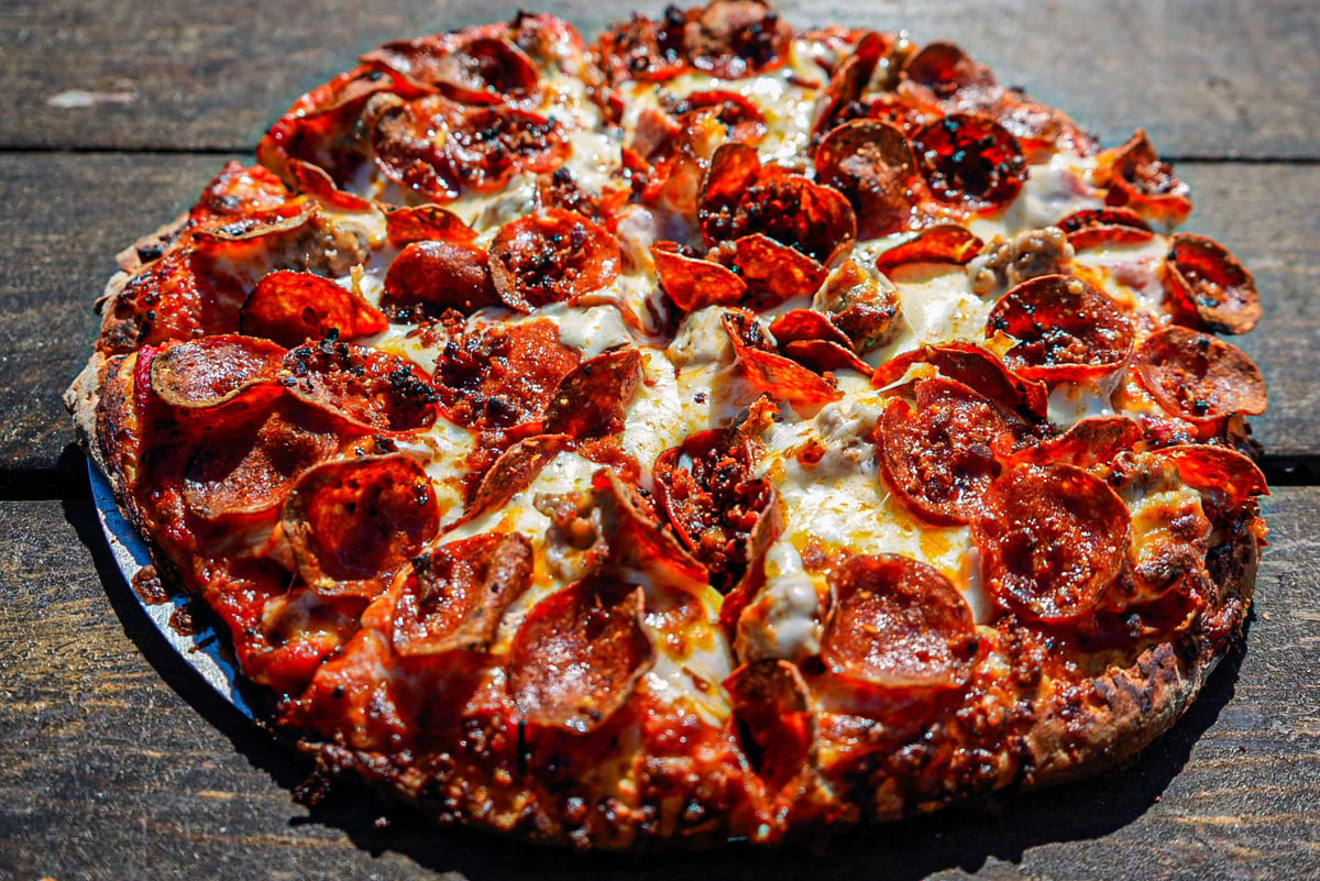 Pepperoni pizza on a blue plate with melted cheese and crispy crust on a wooden surface