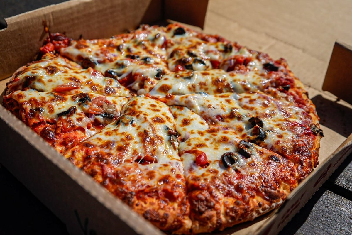 Large pepperoni pizza with vegetables in cardboard delivery box