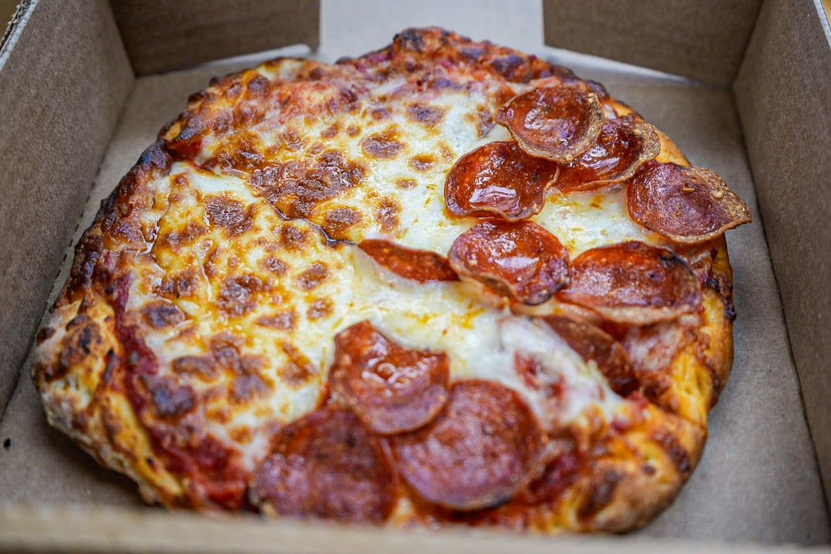 Pepperoni pizza in a cardboard box with melted cheese and crispy crust