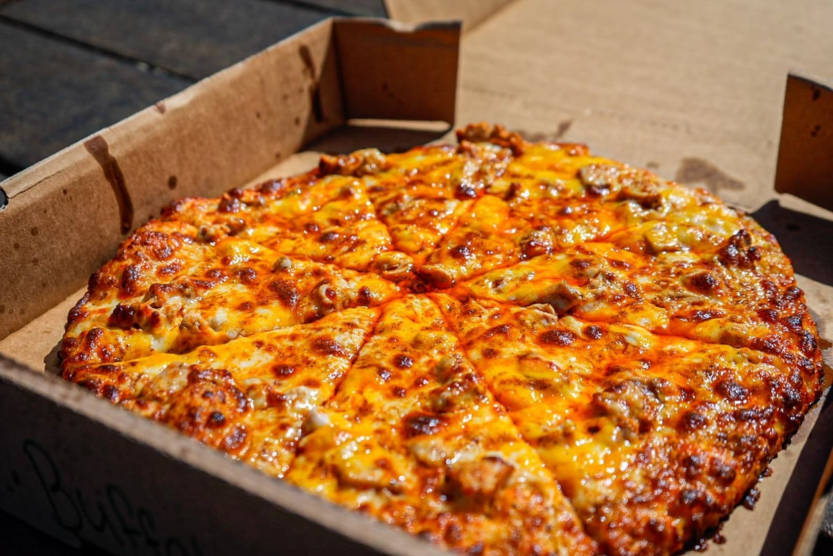 Large pepperoni pizza with melted cheese in an open cardboard delivery box
